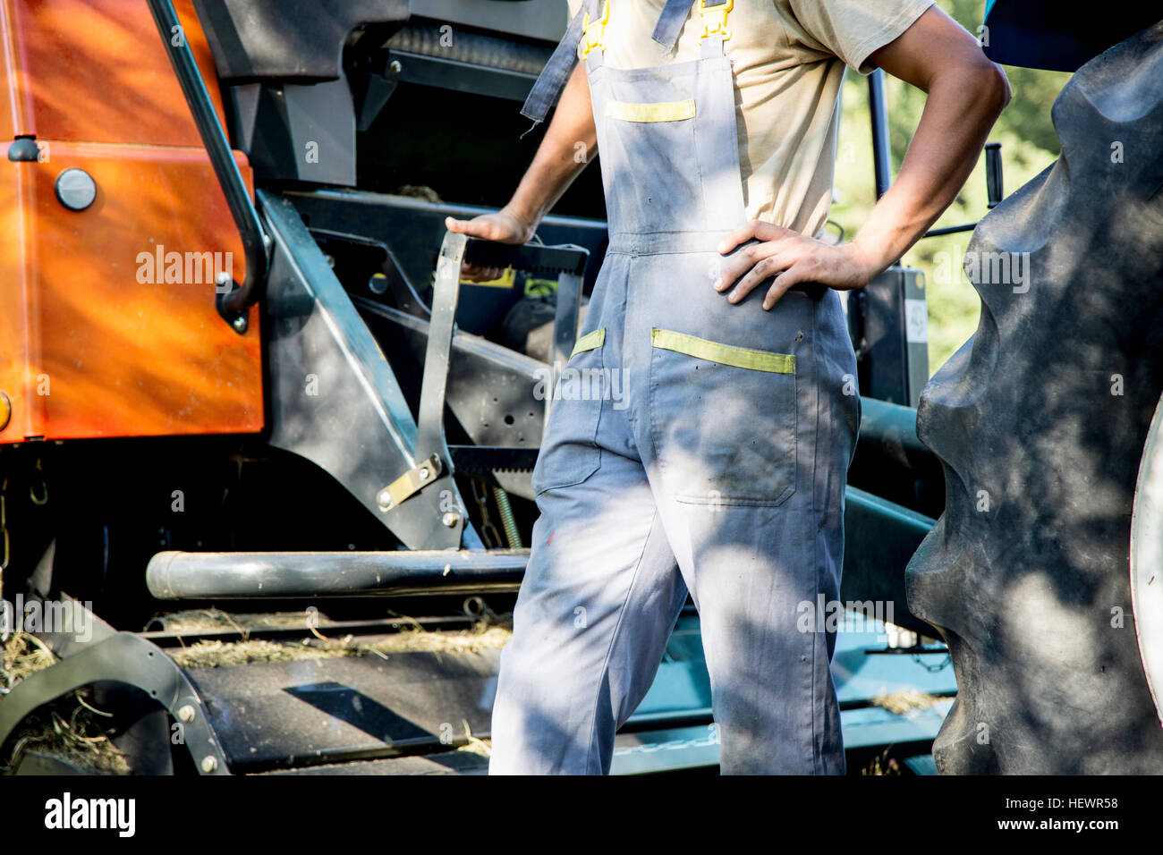 Mid section of male farmworker leaning against tractor Stock Photo