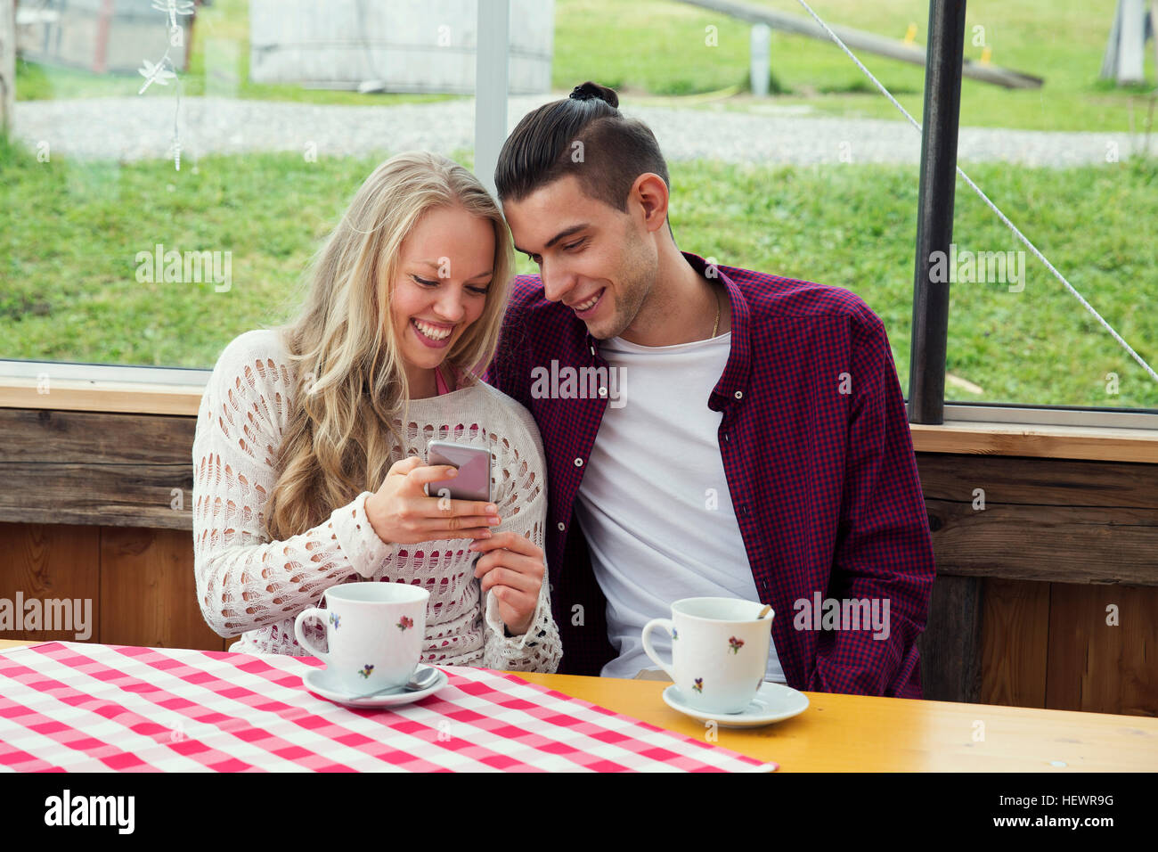 Young couple looking at smartphone update in cafe Stock Photo