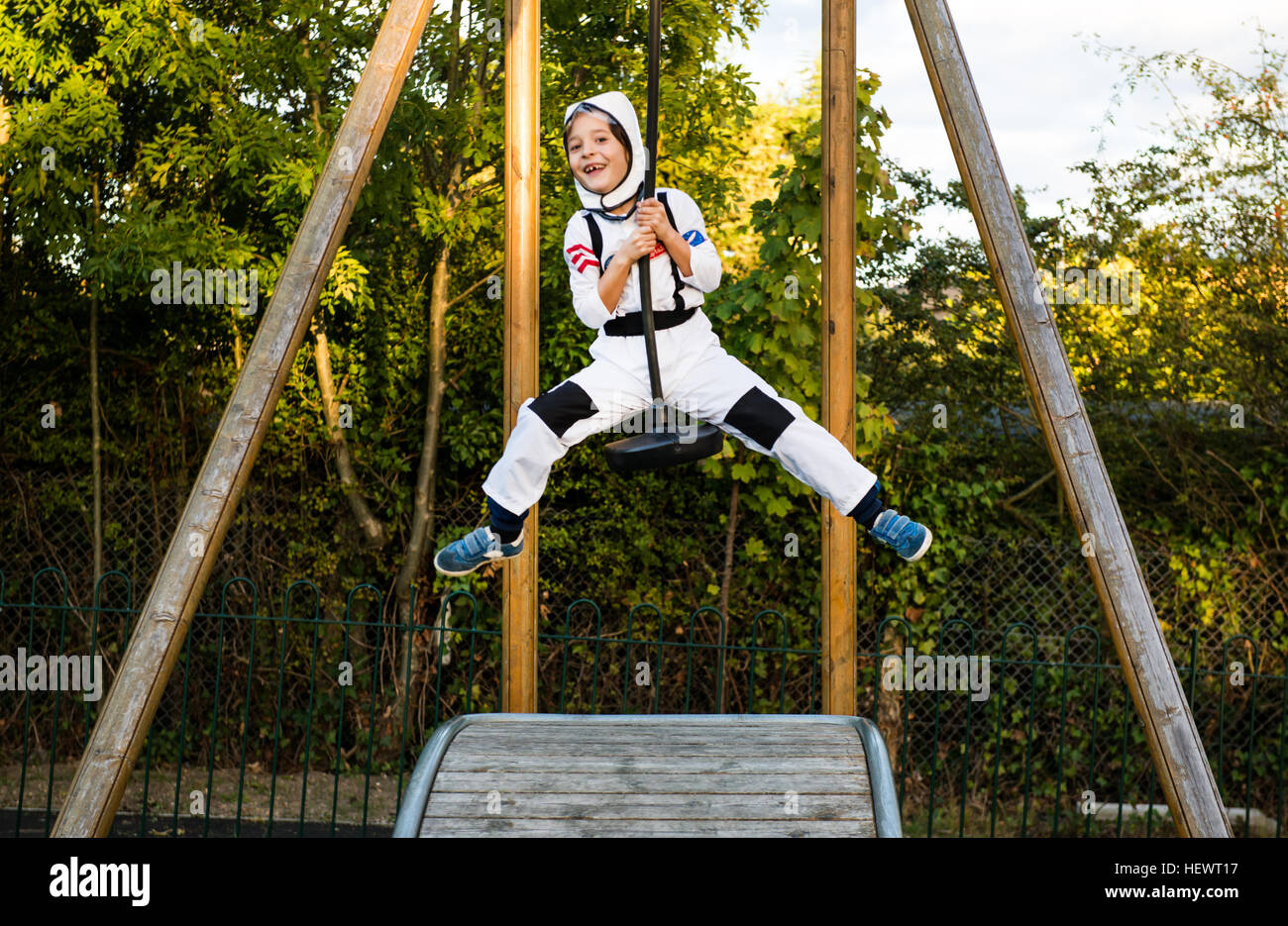 Portrait of boy in astronaut costume riding on playground zip wire Stock Photo