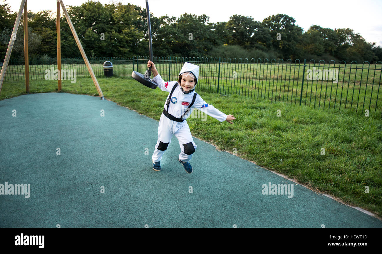 Portrait of boy in astronaut costume pulling playground zip wire Stock Photo