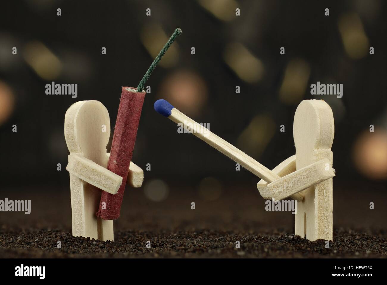 One small wooden male holds a banger and the other one holds a matchstick Stock Photo