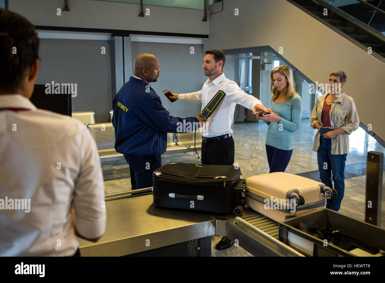 Security guard frisk passengers standing in queue at