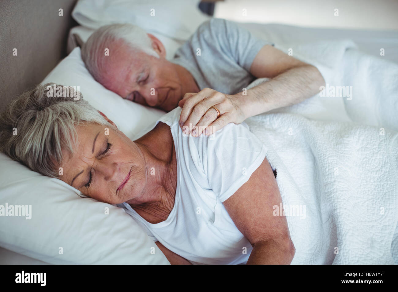 Senior couple sleeping on bed in bedroom Stock Photo - Alamy