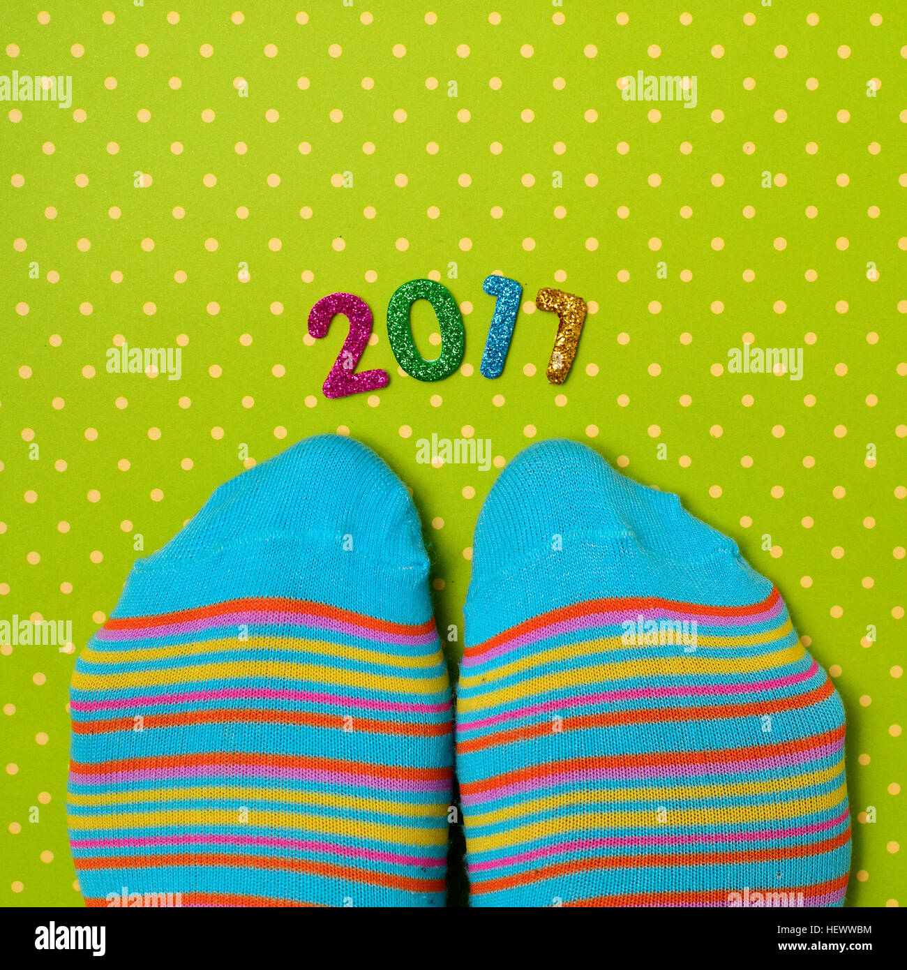high-angle shot of a pair of feet wearing colorful striped socks and some glittering numbers of different colors forming the number 2017, as the new y Stock Photo