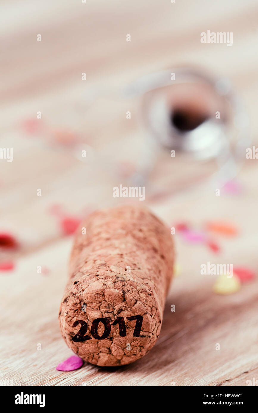 the number 2017, as the new year, written in the cork of a bottle of champagne, on a wooden table full of confetti Stock Photo