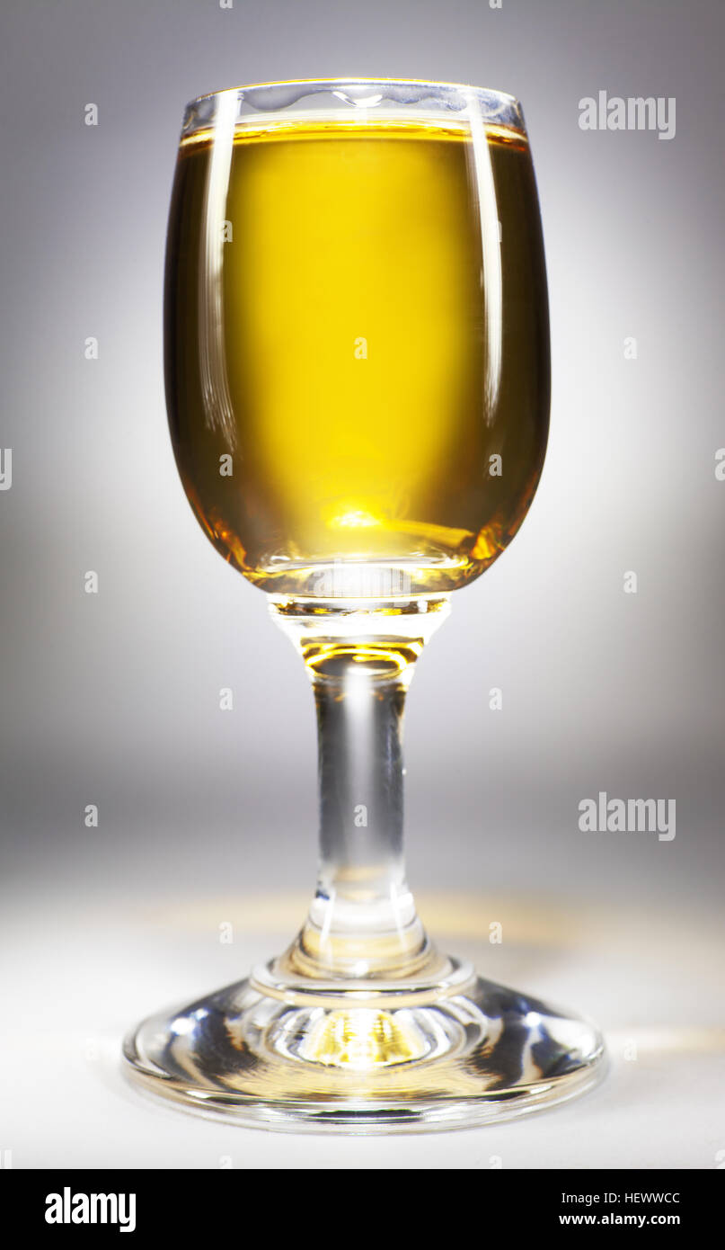 Small glass full of alcoholic drink, closeup view, on white background. Stock Photo