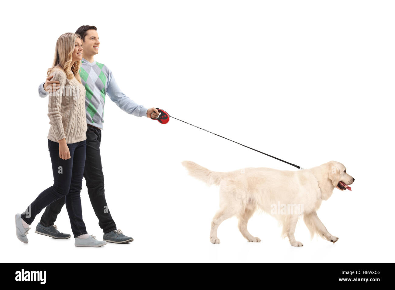 Full length portrait of a happy young couple walking a dog isolated on ...
