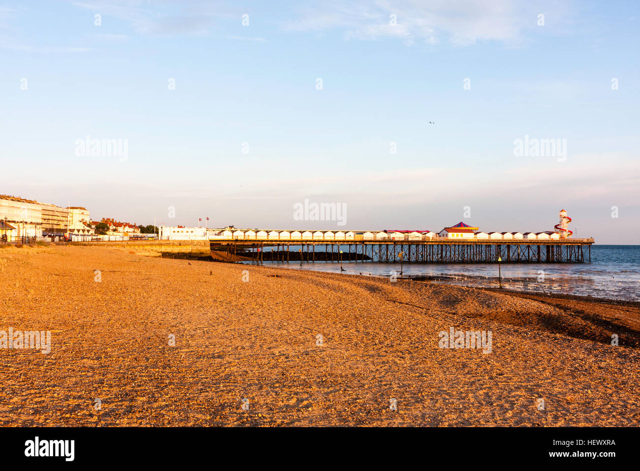 Early morning, golden hour, sunlit view along seafront promenade, beach with the pier in the background at Herne Bay in Kent. Stock Photo