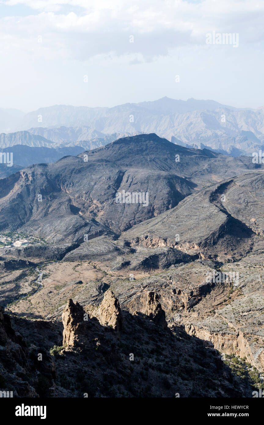 Arid jagged mountains overlook an eroded and inhospitable rocky desert valley. Stock Photo