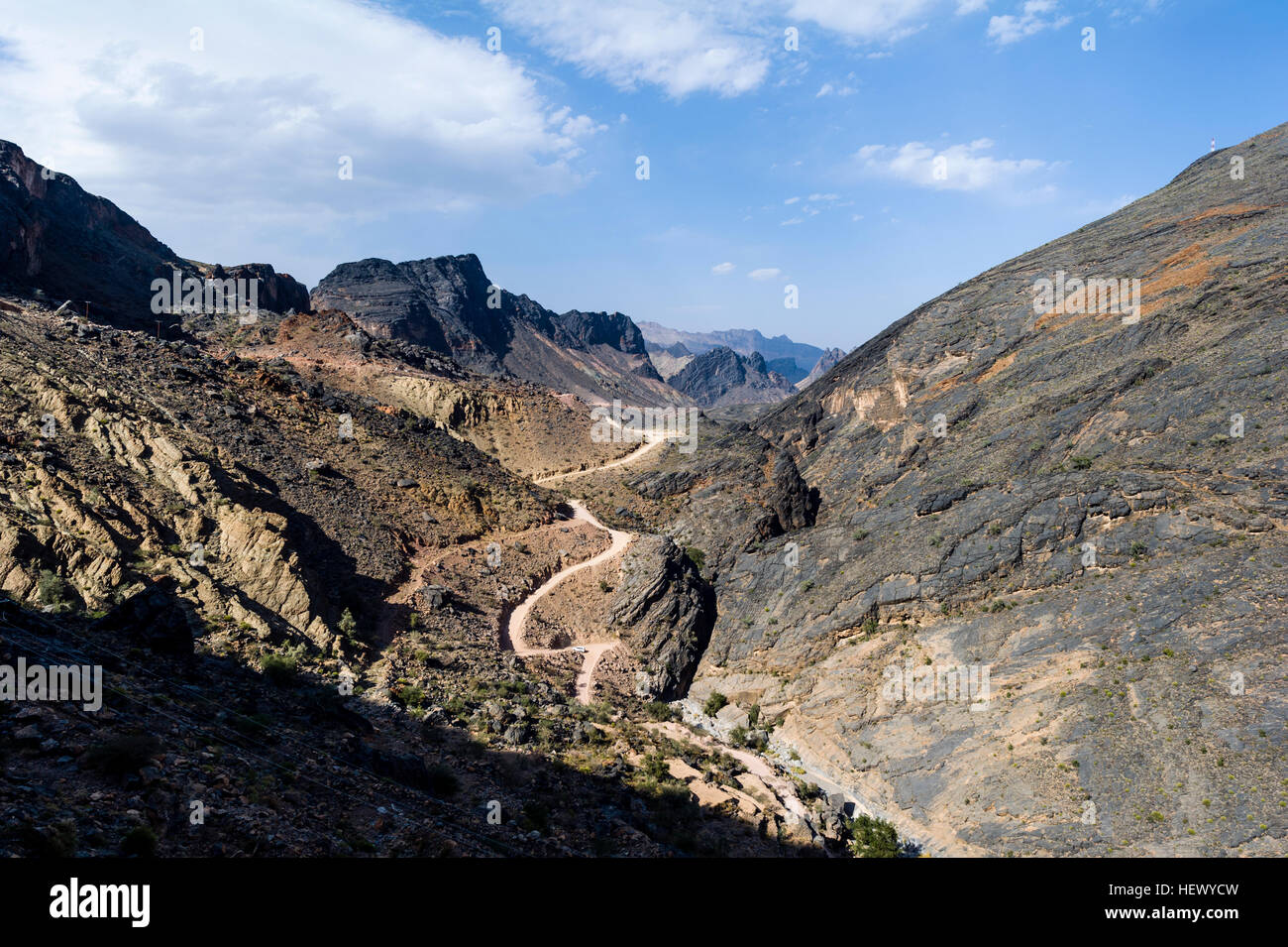 A winding dirt road meanders through a desert mountain pass. Stock Photo