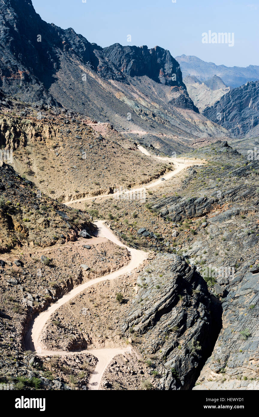 A winding dirt road meanders through a desert mountain pass. Stock Photo