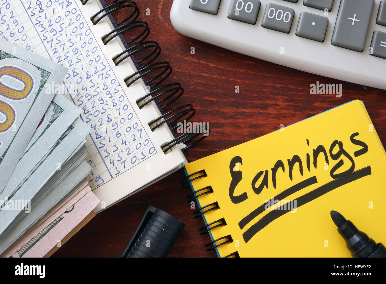 Earnings written in a note, calculator and cash. Stock Photo