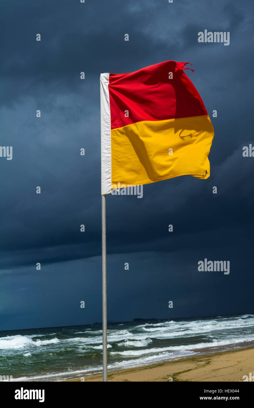 The red and yellow flag of a lifeguard patrol on a stormy beach. Stock Photo