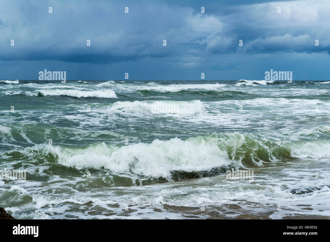 Storm surge waves rolling onto an empty beach. Stock Photo