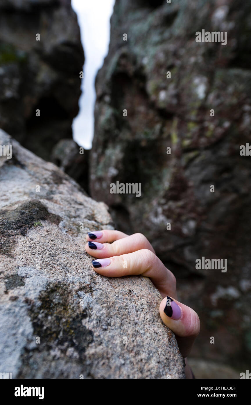 Painted fingernails of a person climbing through rock formations. Stock Photo
