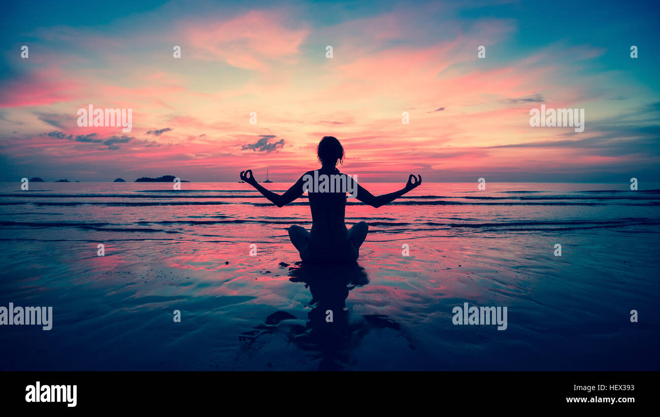 Silhouette young woman practicing yoga on the beach at sunset Stock ...