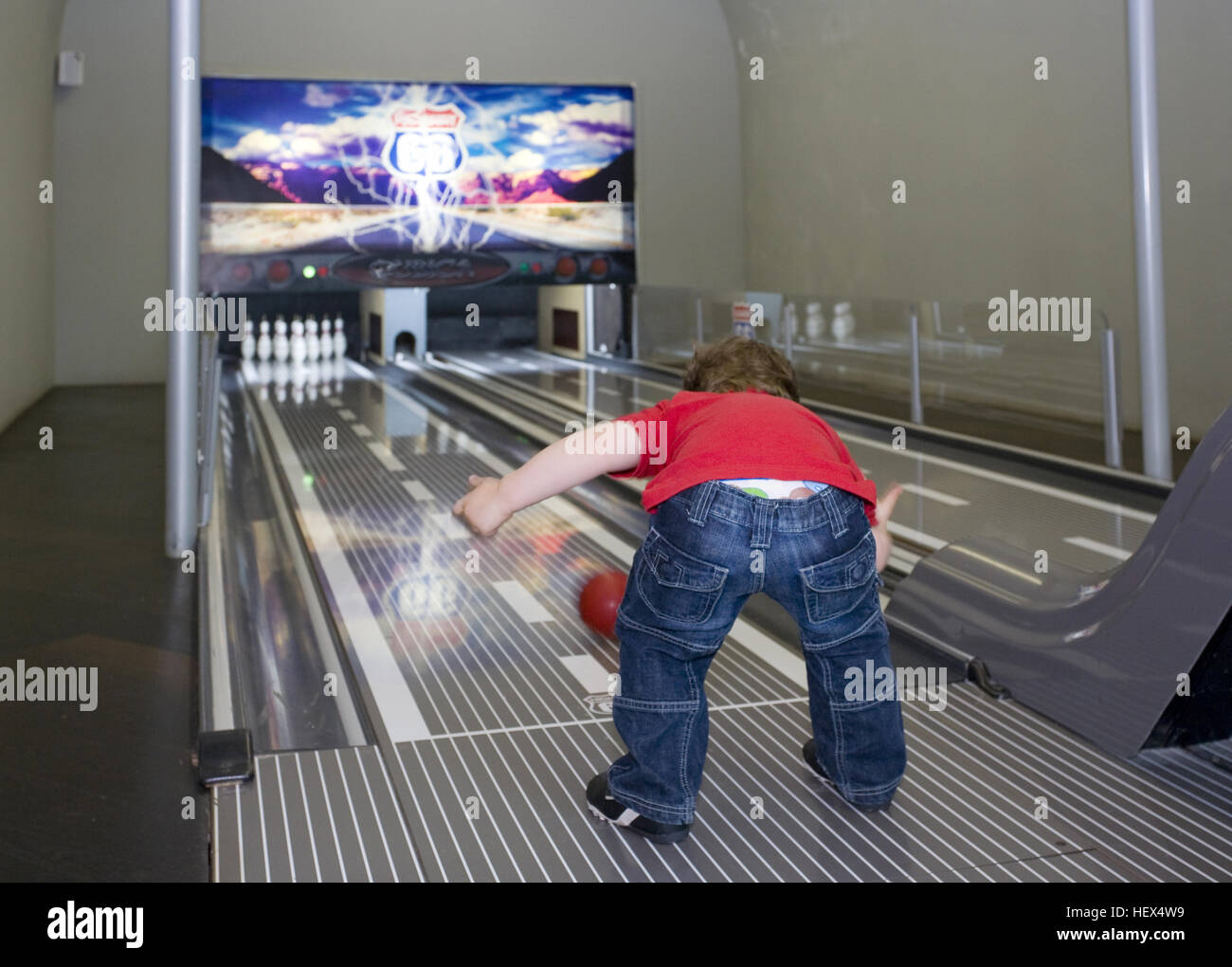 Small child pitches bowling ball down bowling alley, Stock Photo