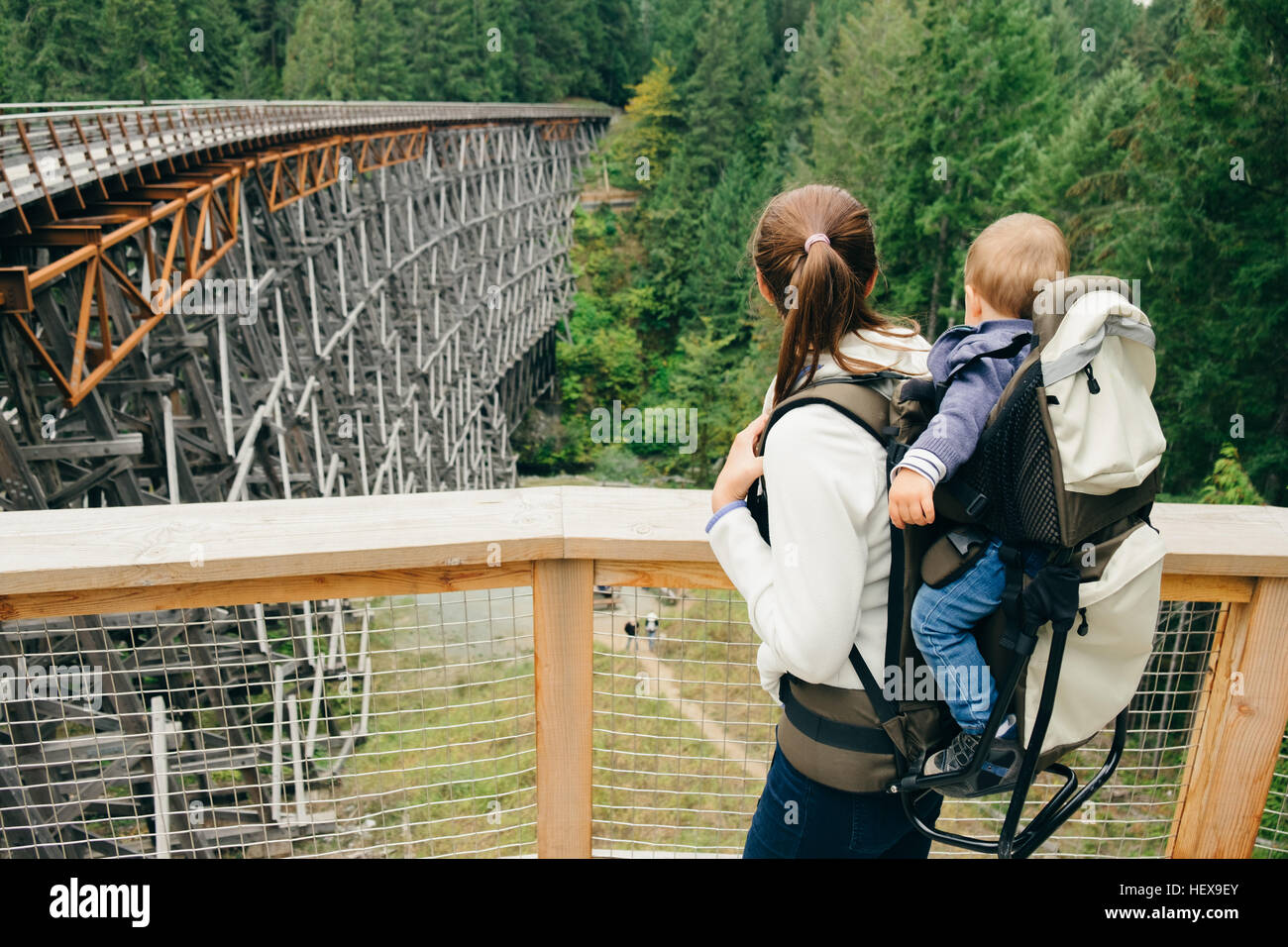 Young woman carrying son on back, rear view, Kinsol Trestle Bridge, British Columbia, Canada Stock Photo