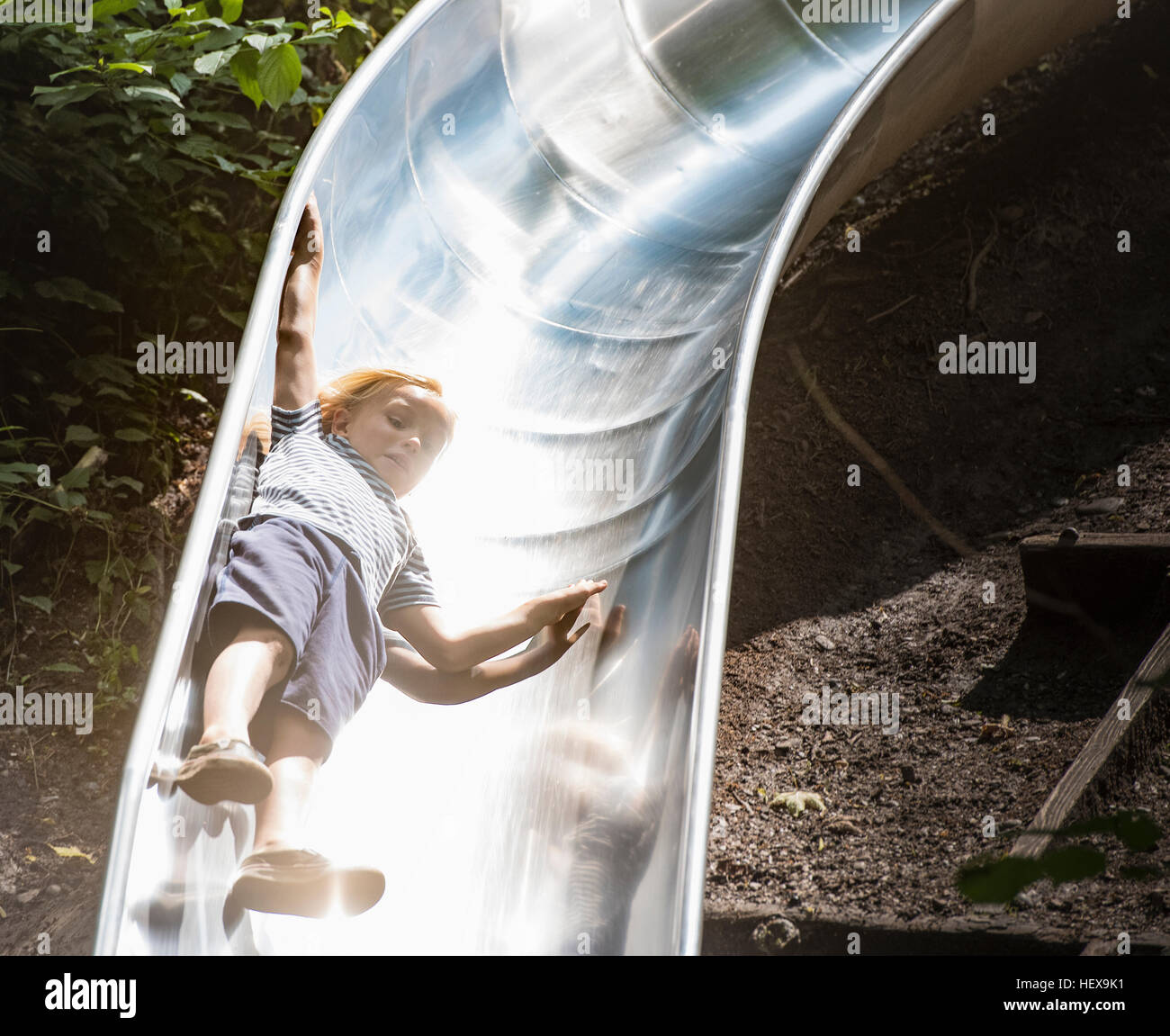 Boy sliding down playground slide Stock Photo