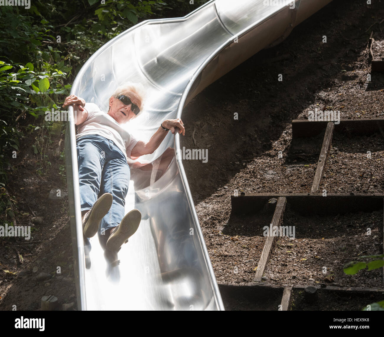 Woman sliding down playground slide Stock Photo