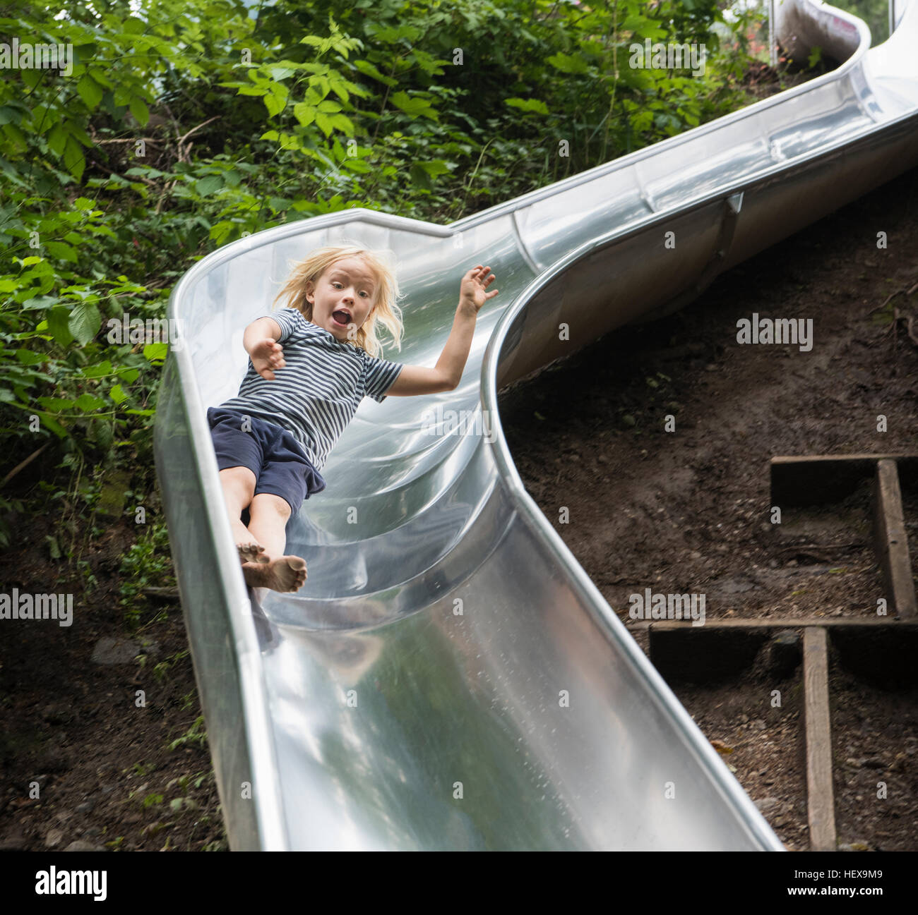 Boy sliding down playground slide Stock Photo