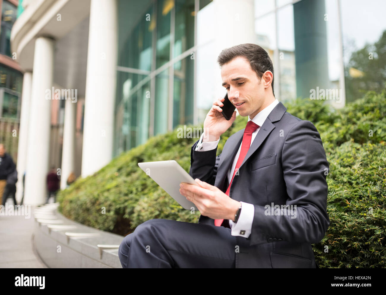 Businessman in city making telephone call, using digital tablet Stock Photo