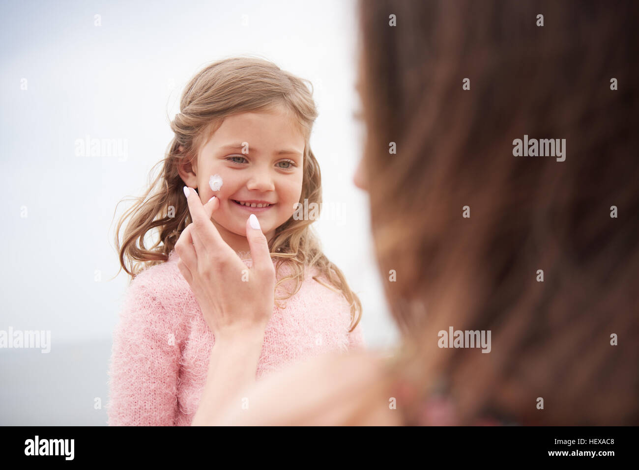Mother applying sun cream on daughter's cheek Stock Photo
