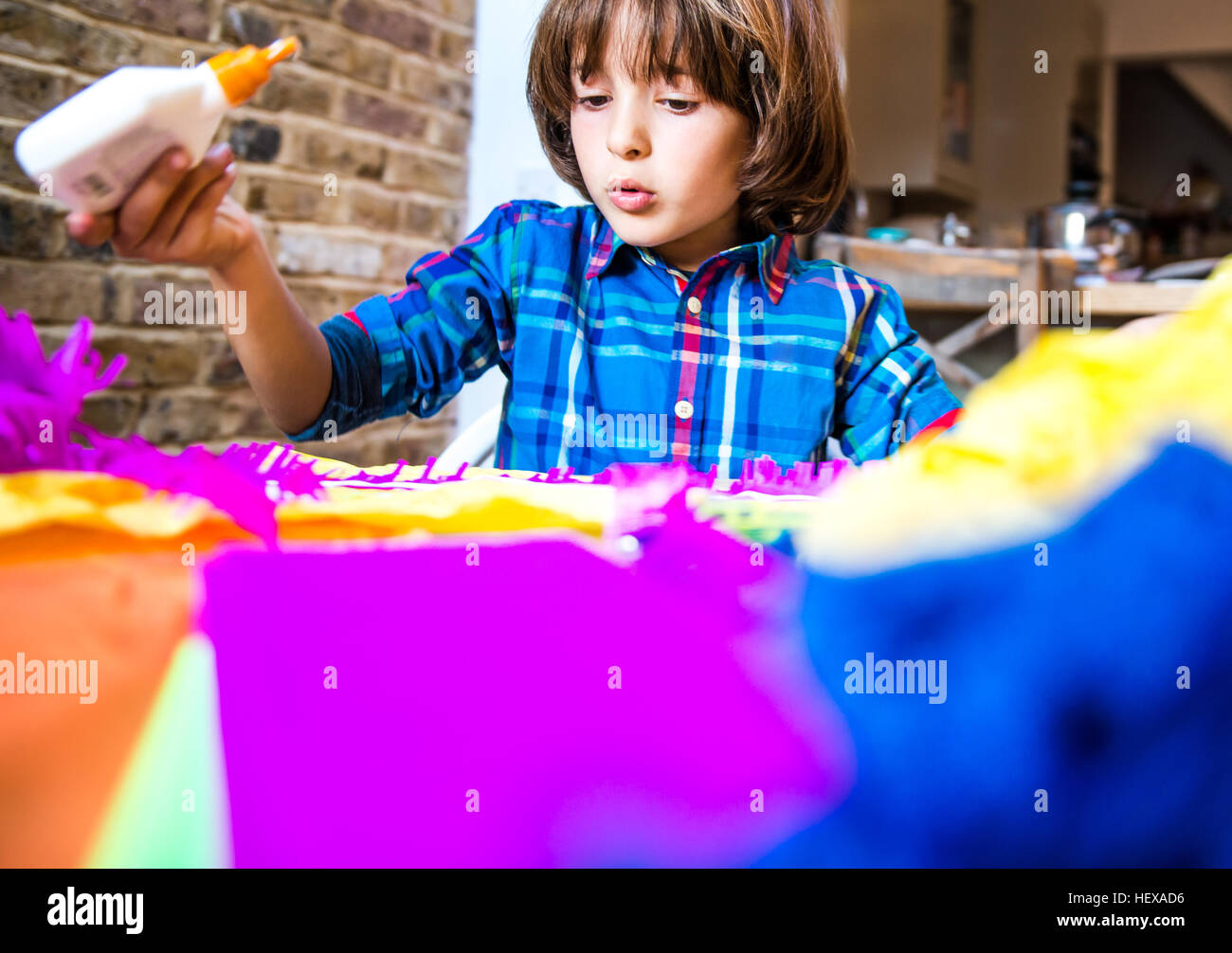 Boy spreading glue on crepe paper to make pinata Stock Photo
