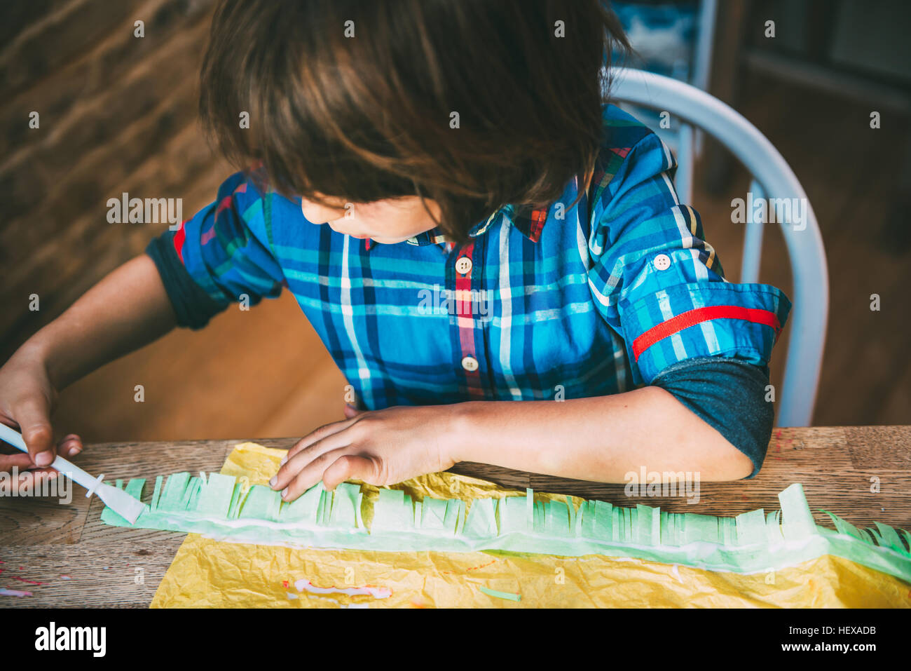 Boy spreading glue on crepe paper to make pinata Stock Photo Alamy