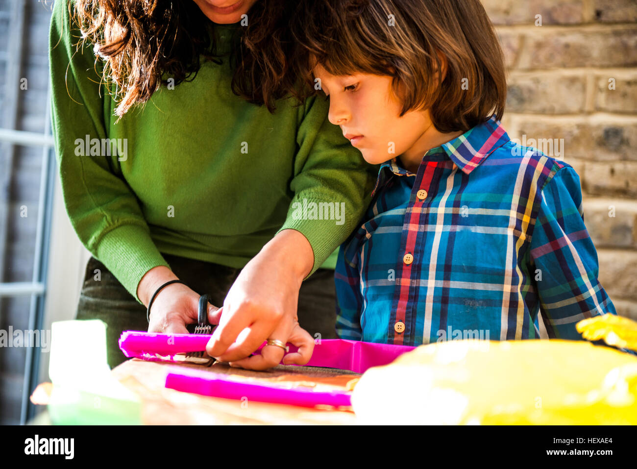Mother and son cutting crepe paper to make pinata Stock Photo Alamy
