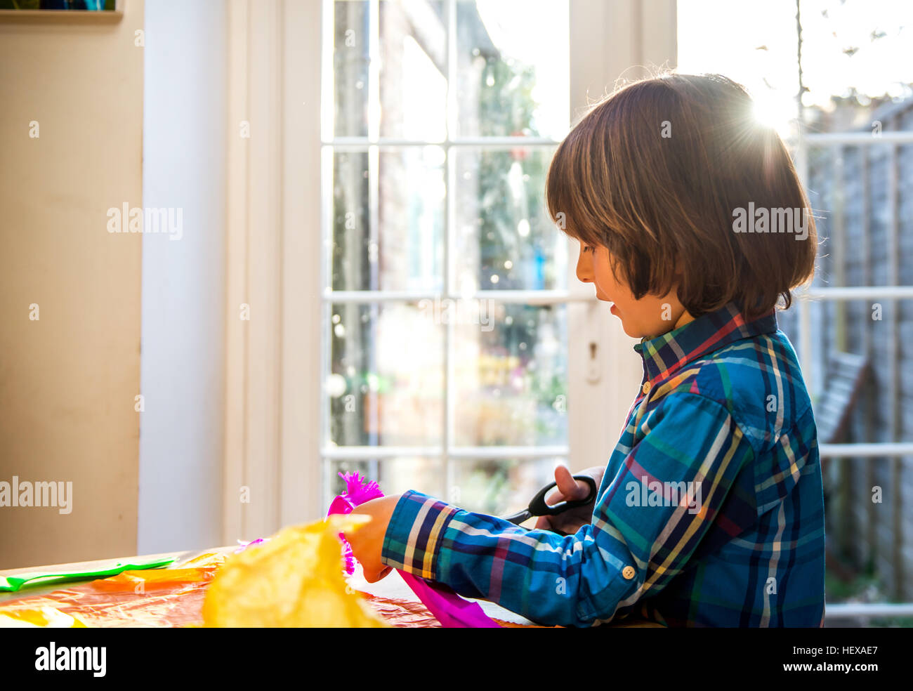 Boy cutting crepe paper to make pinata Stock Photo Alamy