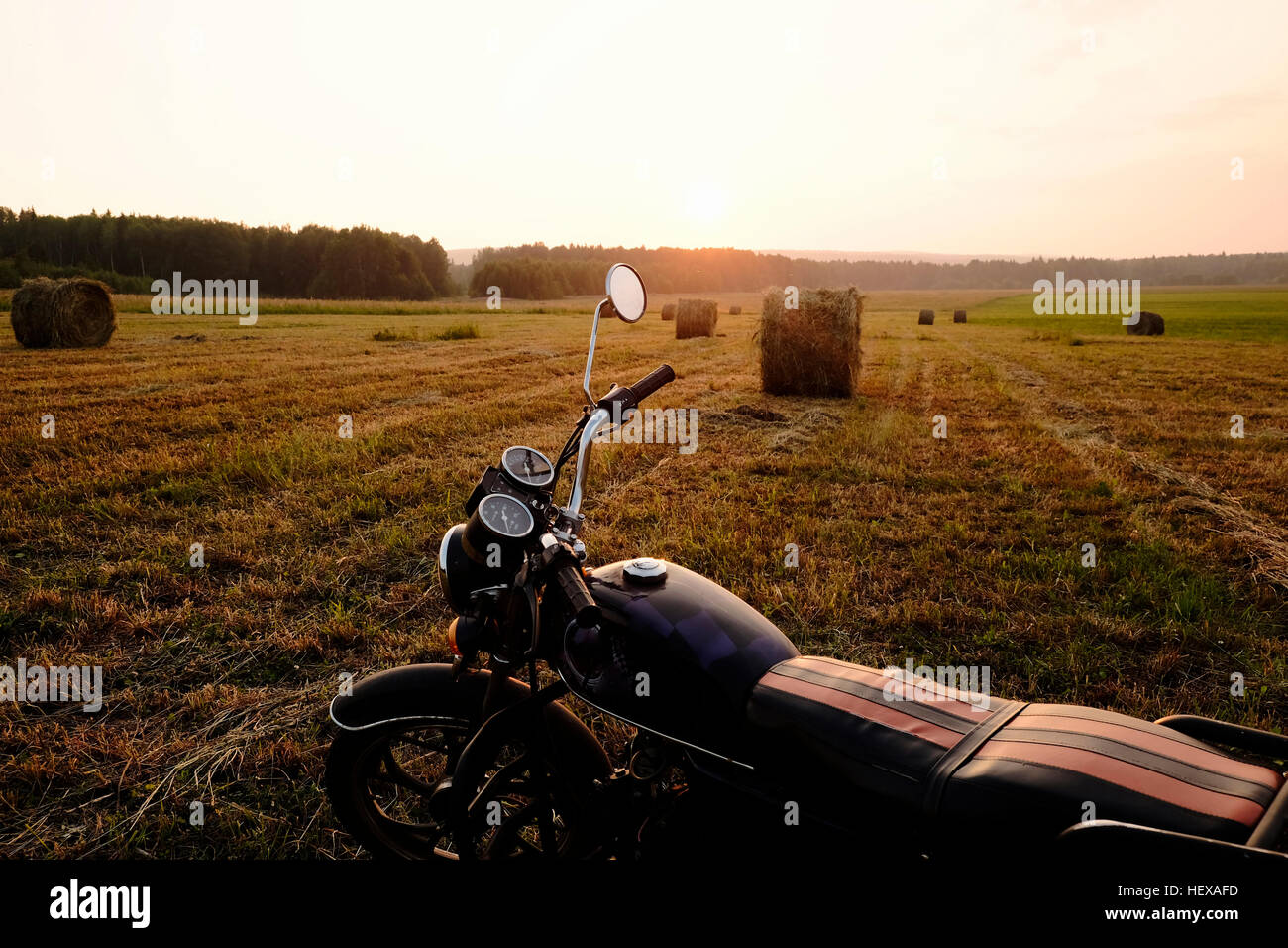 Motorbike parked in field at sunset, Ural, Russia Stock Photo