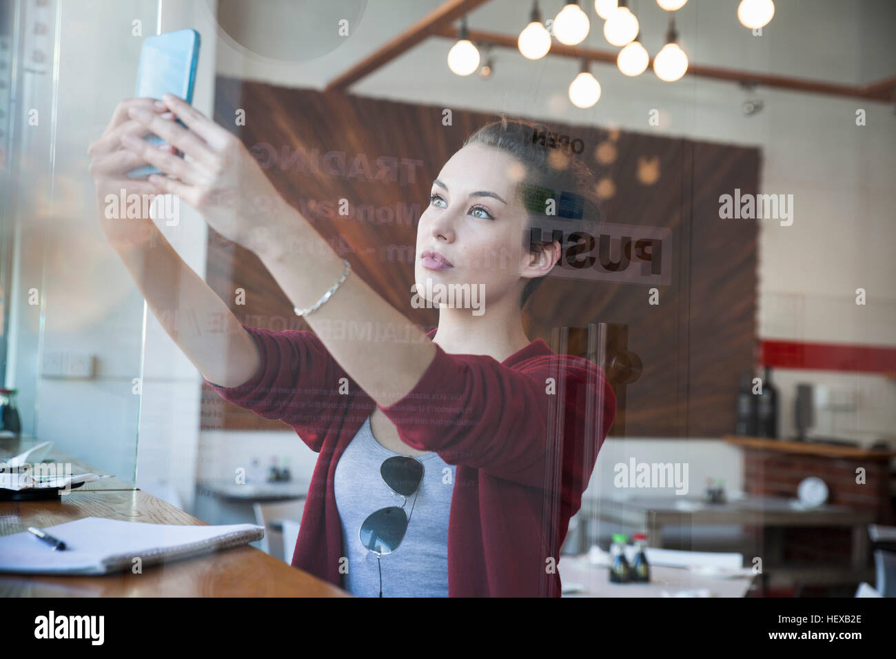 Young woman sitting in cafe, taking selfie, using smartphone Stock Photo