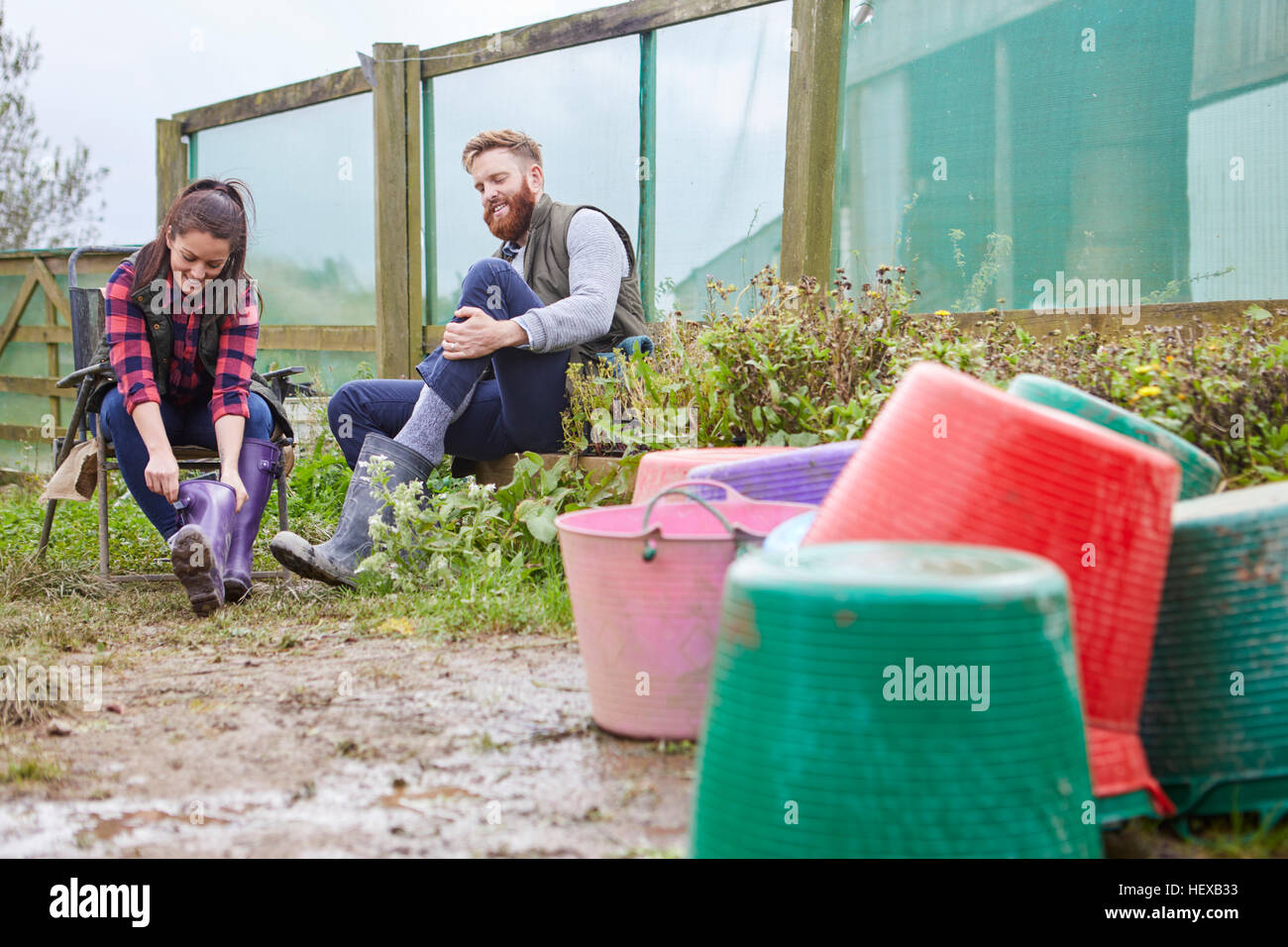 Young couple on farmland putting on rubber boots Stock Photo