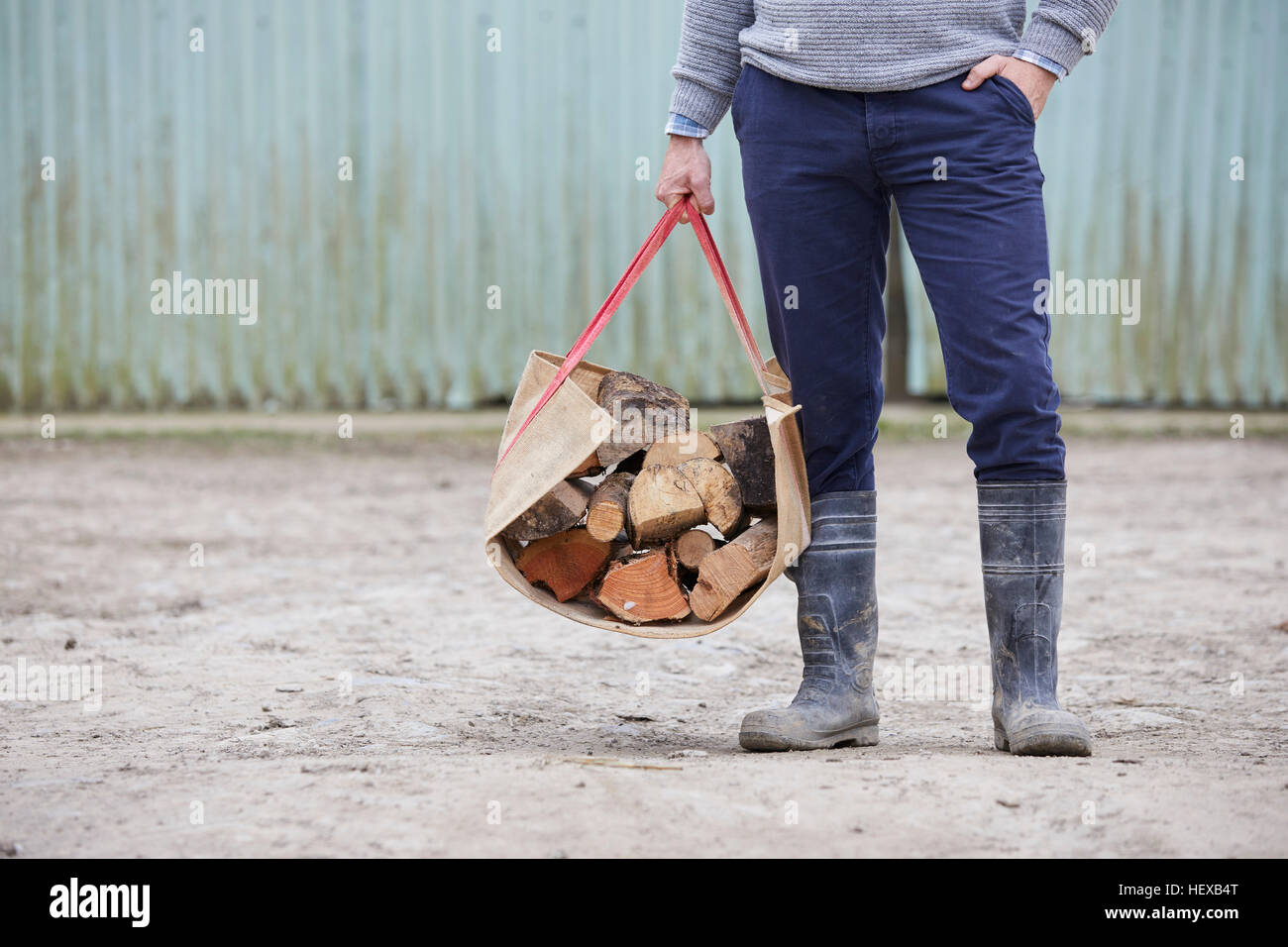Waist down of man holding logs in log carrier Stock Photo