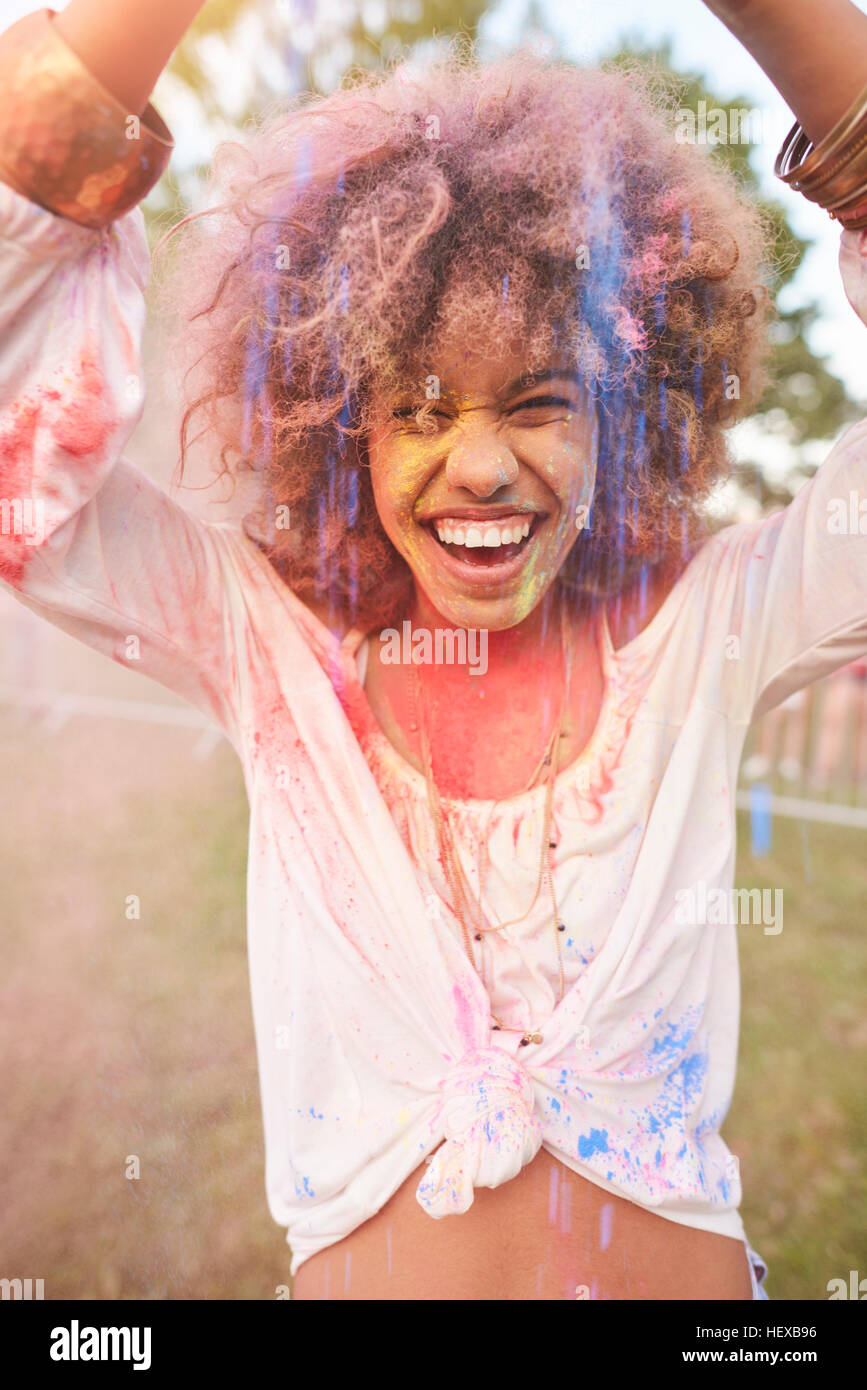 Portrait of young woman at festival, covered in colourful powder paint Stock Photo