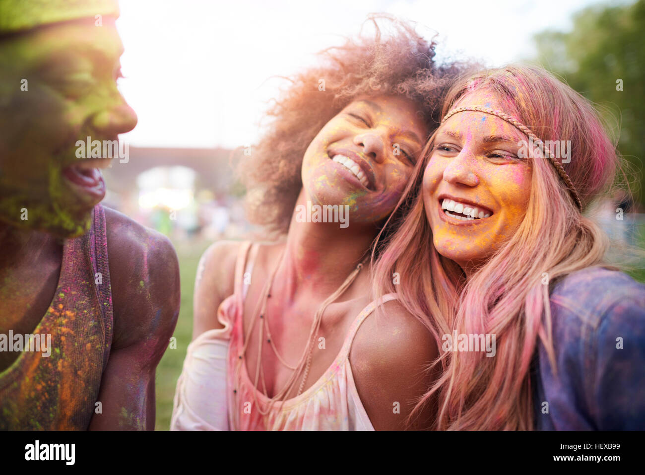 Group of friends at festival, covered in colourful powder paint Stock Photo