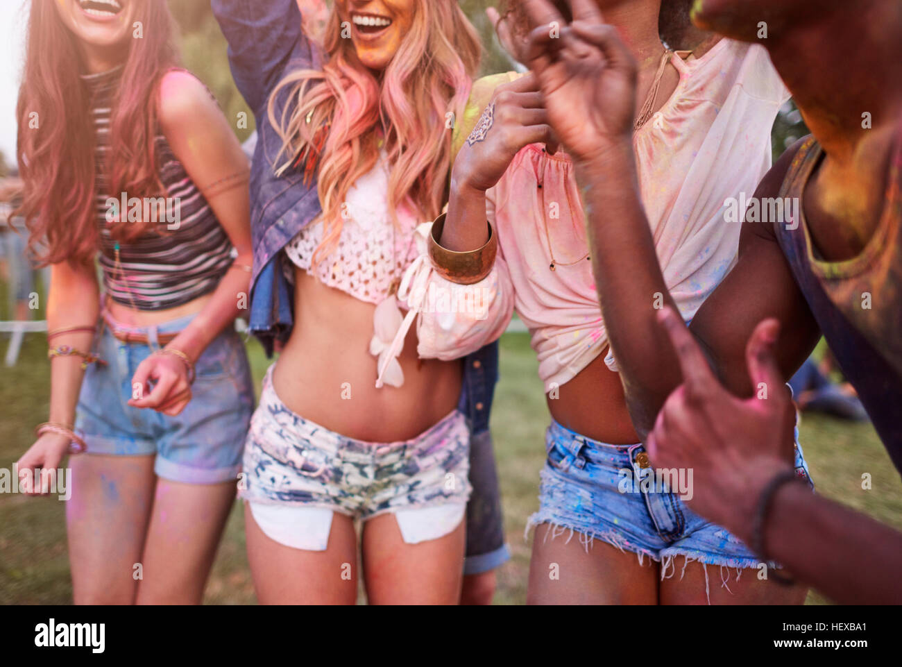 Group of friends at festival, covered in colourful powder paint, mid section Stock Photo