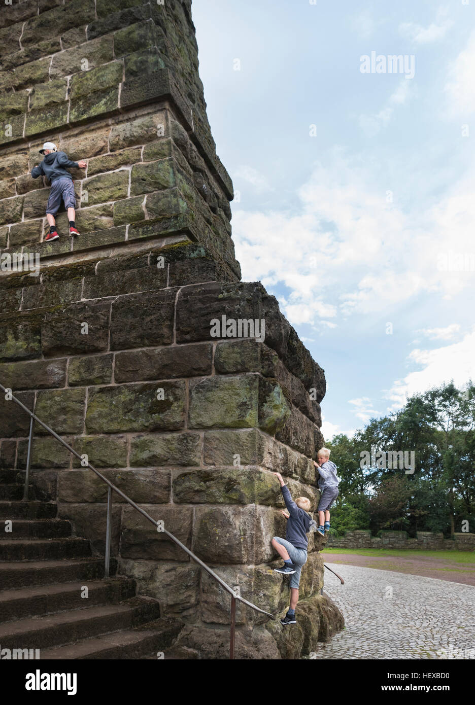 Boys climbing stone wall Stock Photo