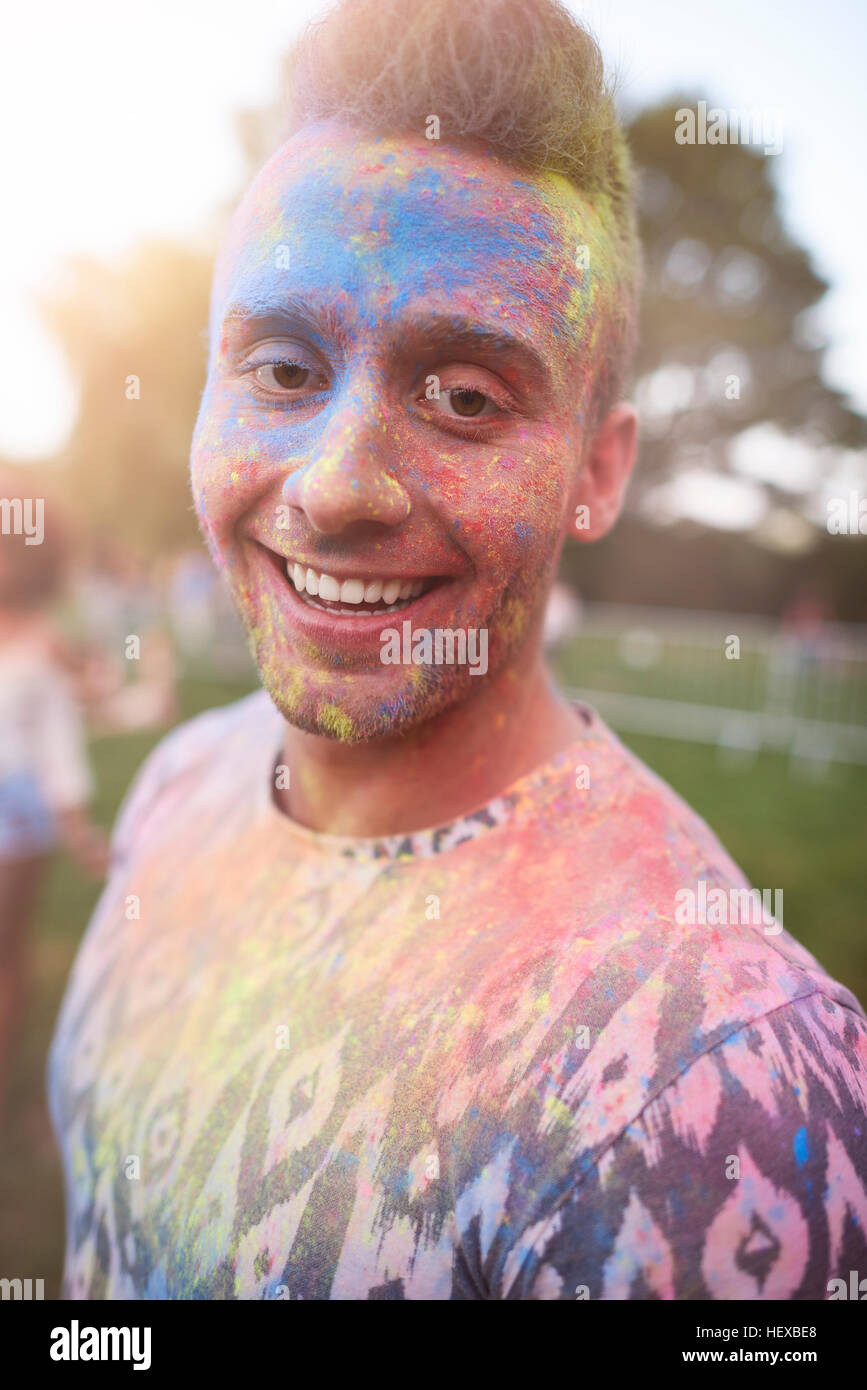 Portrait of young man at festival, covered in colourful powder paint Stock Photo