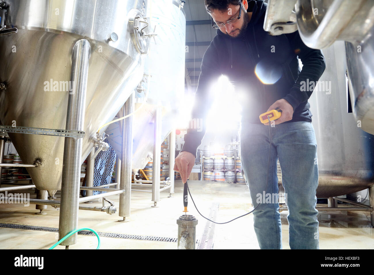 Worker in brewery, checking the temperature of water in brew tank Stock
