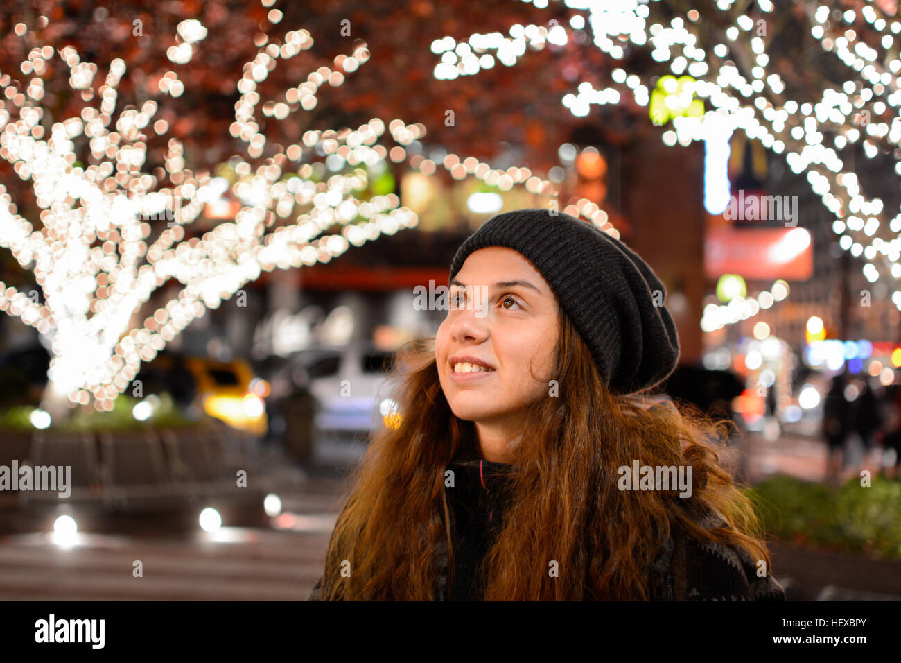 Pretty girl and with festive lights on trees in background Stock Photo