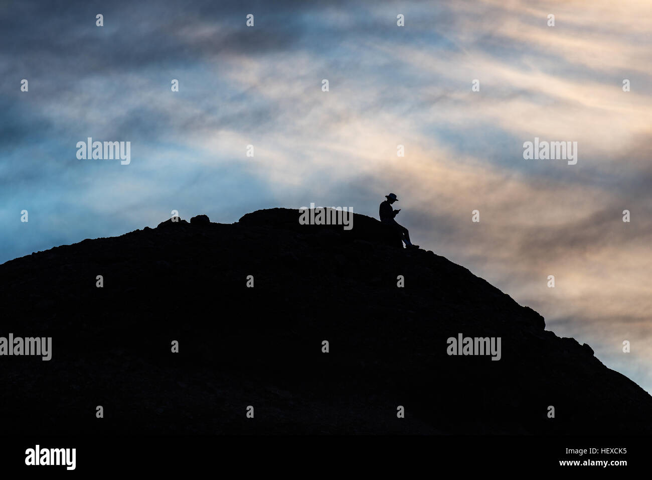 Silhouette of a man on a mountain using a cell phone Stock Photo