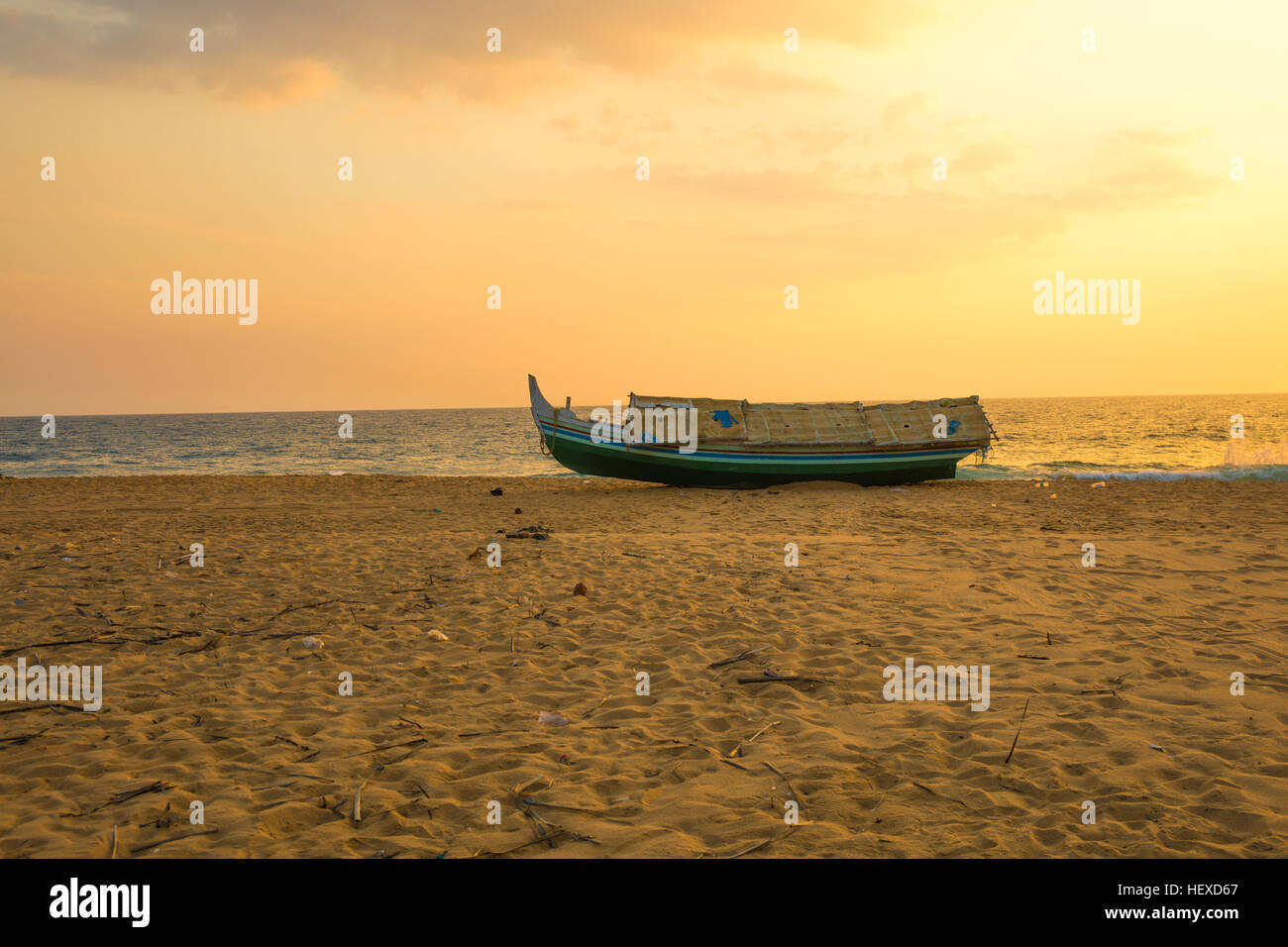 An old traditional fishing boat on the coast of Kerala Beach under a golden sunset Stock Photo