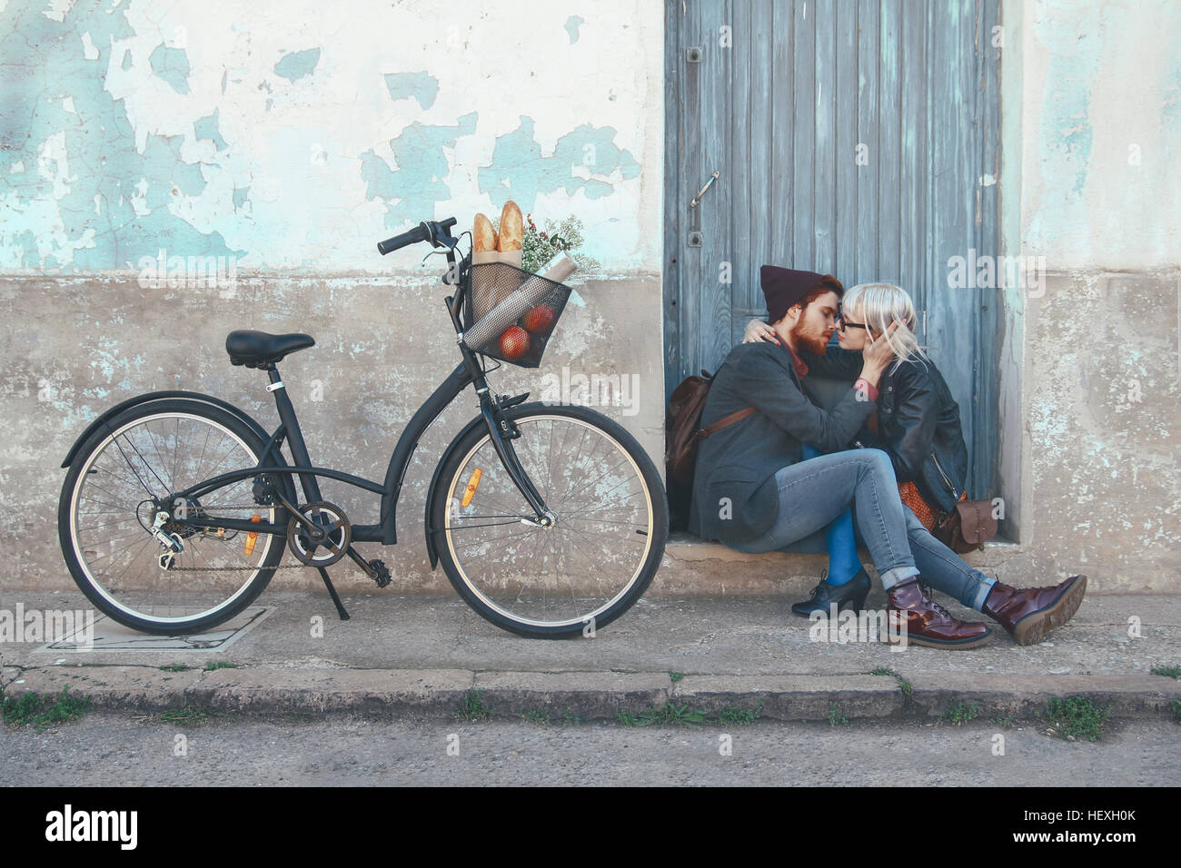 Young couple in love kissing on door step next to a bike Stock Photo