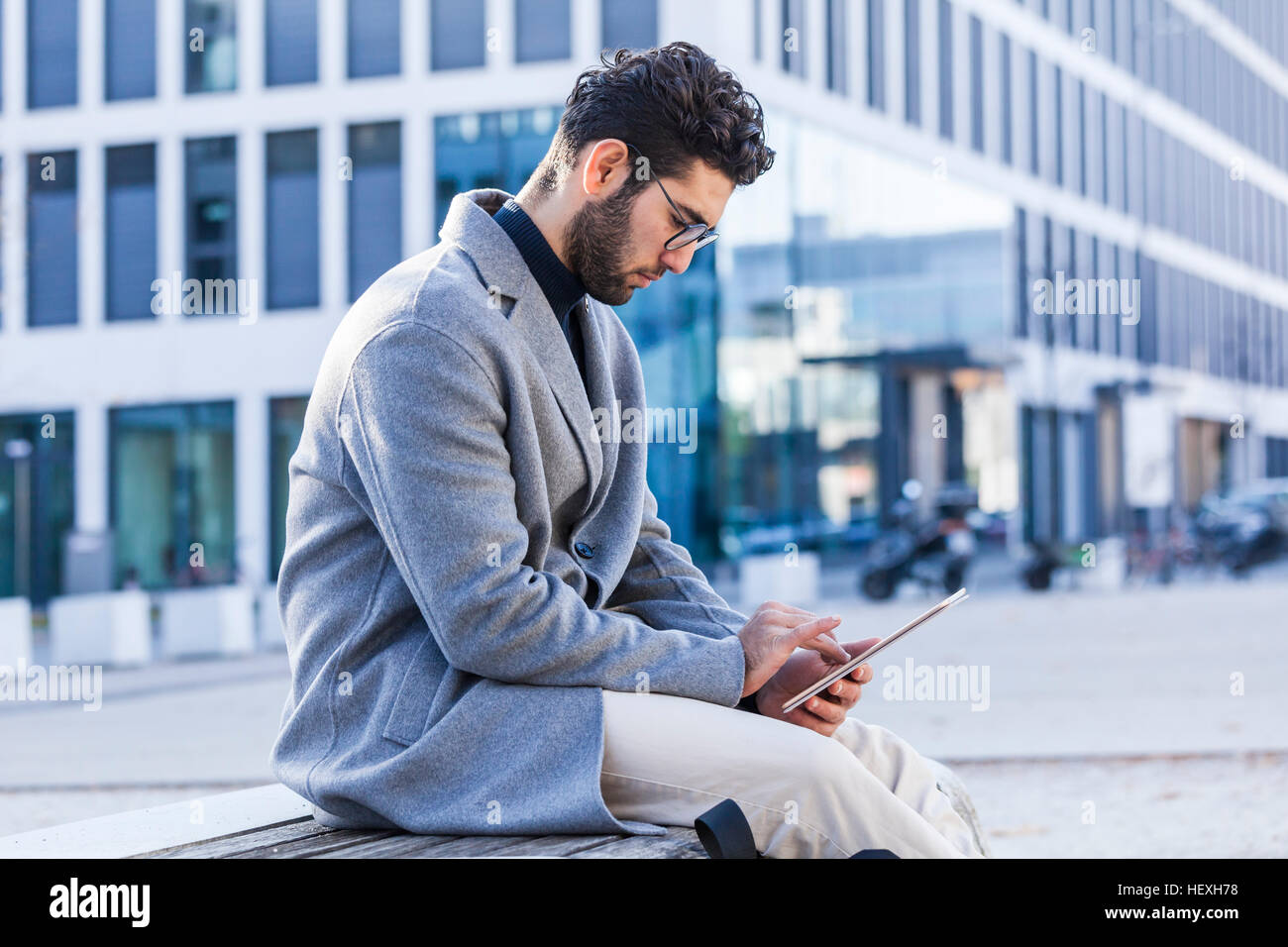 Young man sitting on bench using mini tablet Stock Photo