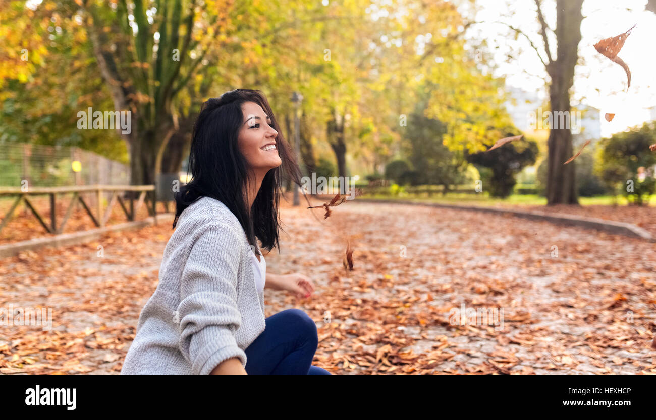 Happy young woman playing with leaves in a park in autumn Stock Photo ...