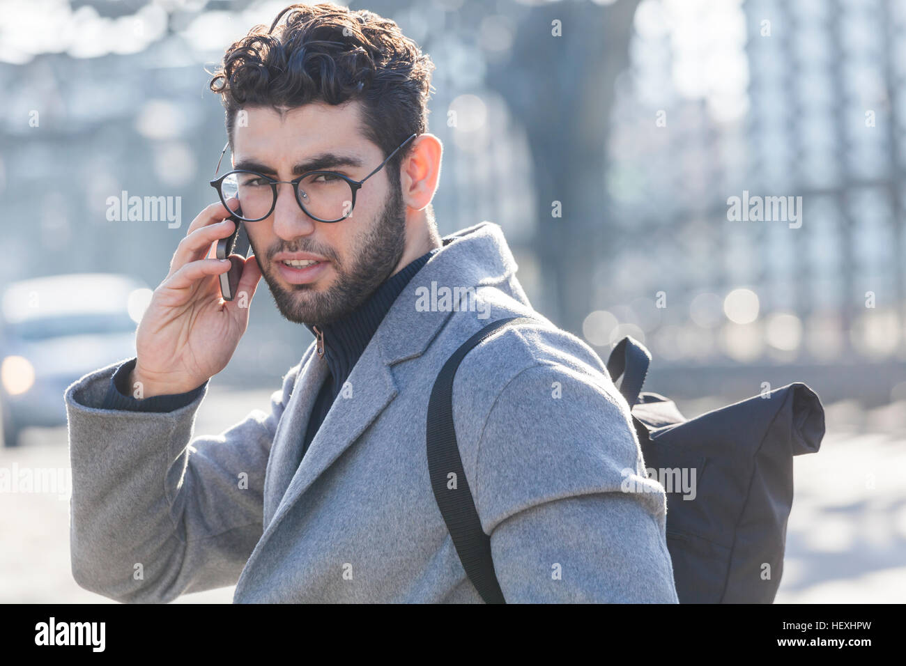 Portrait of young businessman with backpack on the phone Stock Photo