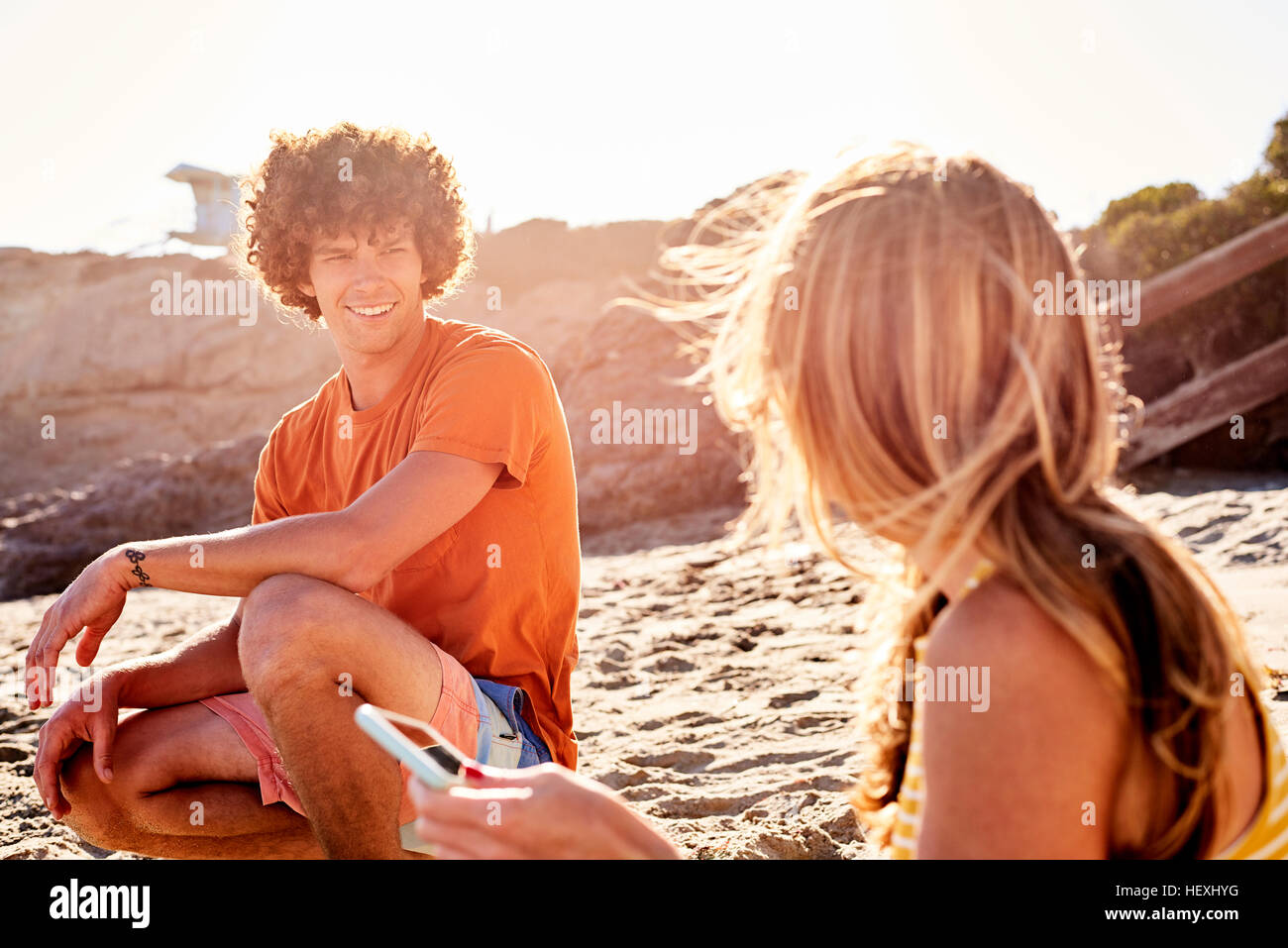 Young man looking at woman on the beach Stock Photo - Alamy