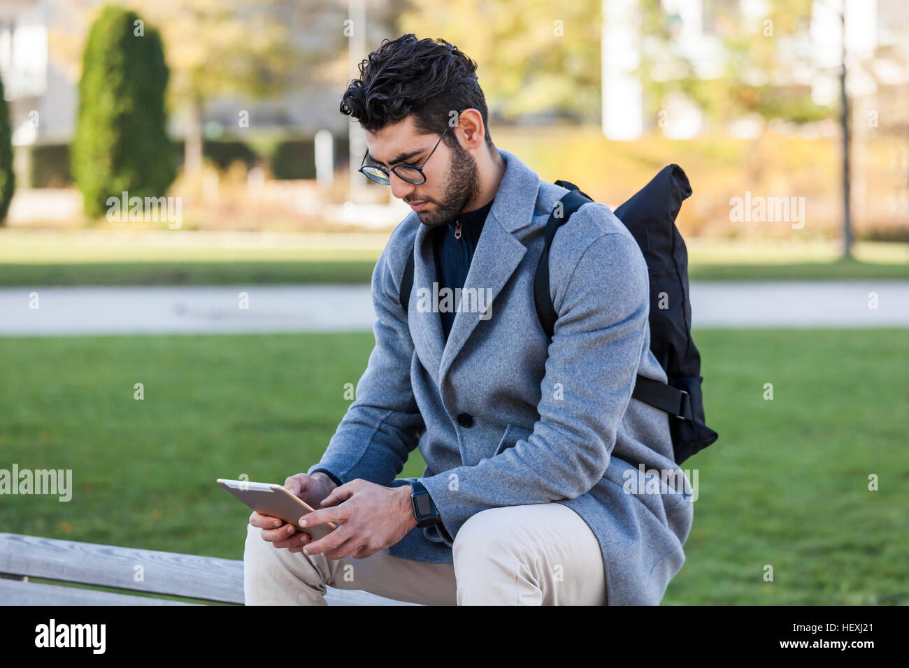 Young man sitting on bench using mini tablet Stock Photo